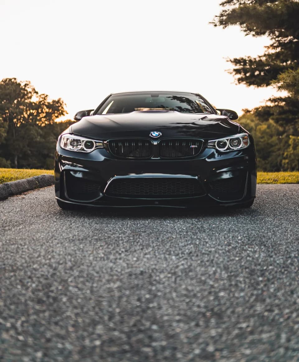 Black car photographed on a quiet road at sunset