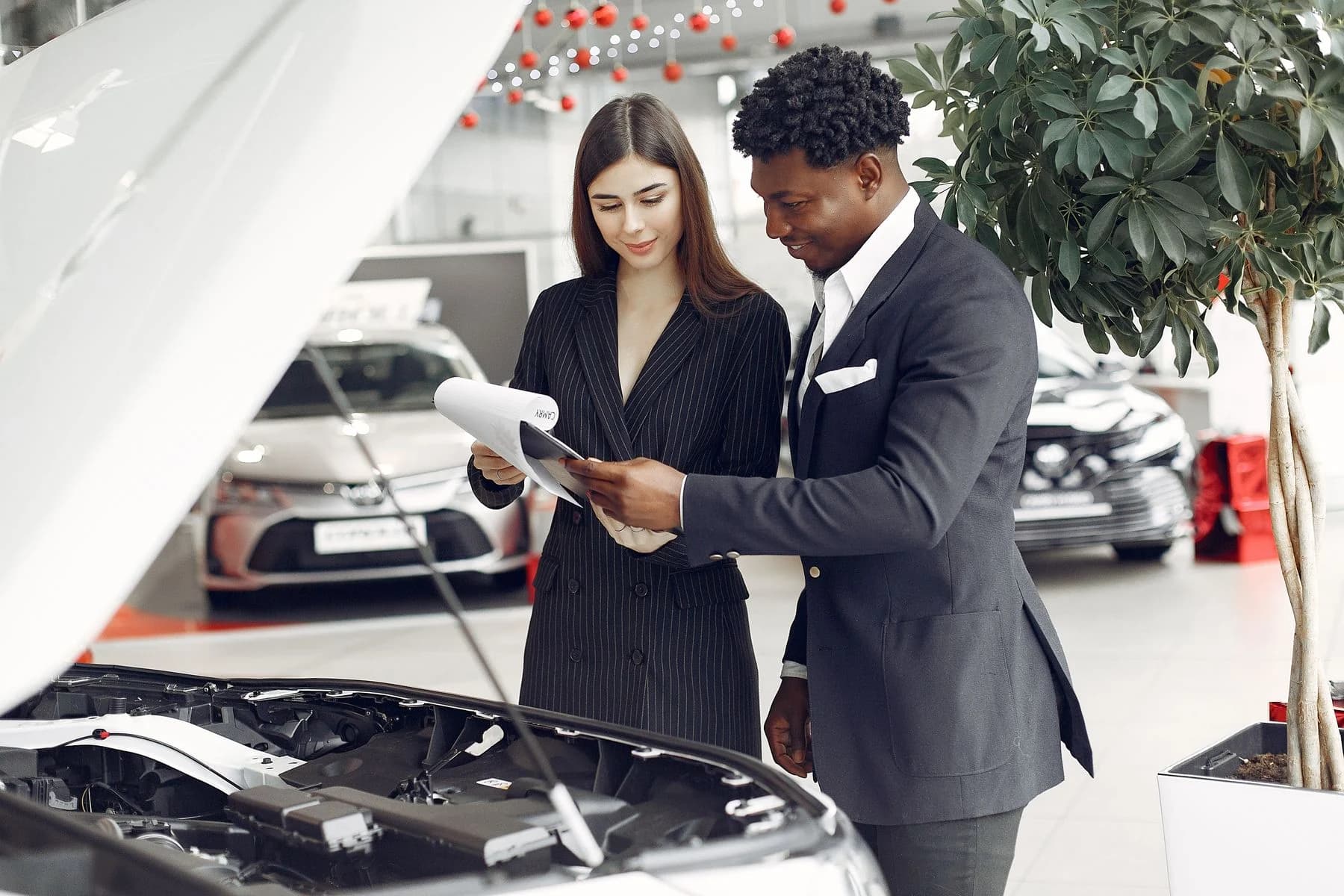 A vehicle specialist reviewing documents beside a car